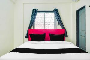a bed with a pink headboard in a bedroom at Hotel O Laxmi Chowk Hinjewadi in Pune +10 photos