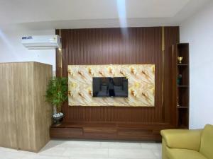 Plus 33 Hotel في Sakumona: غرفة معيشة بها تلفزيون بشاشة كبيرة مثبت على الحائط