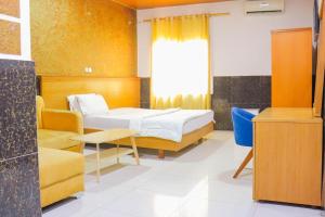 a bedroom with a bed and a chair and a window at Brazza Hôtel in Brazzaville