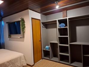a bedroom with a bed and a window and shelves at Flamboyant Residence in Fernando de Noronha