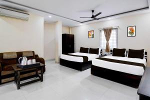 a bedroom with two beds and a table and a couch at Hotel O Kapilatheertham Bus Terminal Tirumala in Tirupati
