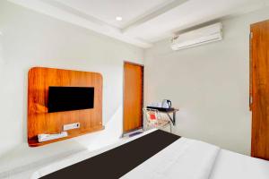 a bedroom with a bed and a tv on the wall at Hotel O Ujjain City Centre in Ujjain