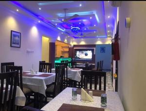 a dining room with tables and chairs and a tv at Lizab Lodge in Sepasi