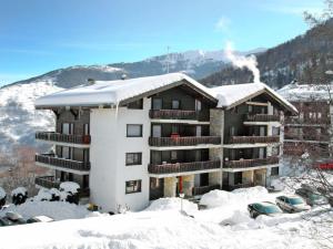 un edificio de apartamentos cubierto de nieve con nieve en el techo en Résidence Arnica 3 pièces, en Nendaz