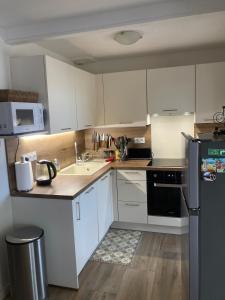 a kitchen with white cabinets and a black refrigerator at Chez Thierry - appartement vue mer grande terrasse in Saint-Aygulf