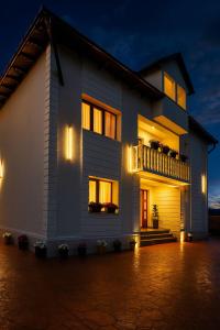 a white house with a balcony at night at Pensiunea Alexia in Novaci
