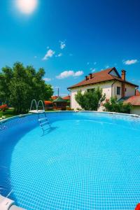 a swimming pool with a chair in front of a house at Pensiunea Alexia in Novaci