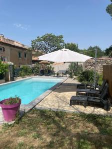 una piscina con due lettini e un ombrellone di Douceur occitane a Saint-Chinian