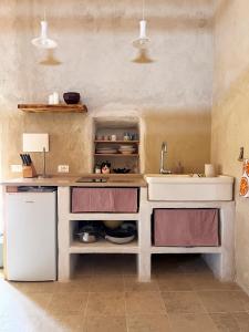 a kitchen with a sink and a counter and a refrigerator at La casetta La Vita in land in Burgio