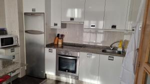 a kitchen with white cabinets and a stainless steel refrigerator at Alojamiento Misericordia in Viveiro