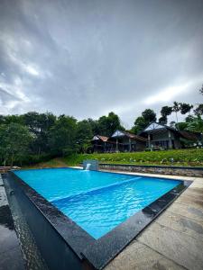 a large blue swimming pool in front of a house at Meghamalhar in Mānantoddy