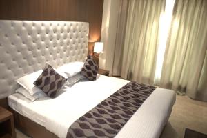 a bedroom with a large white bed with pillows at Hotel Sai Sanidhya in Thane