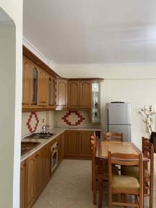 a kitchen with wooden cabinets and a table and a refrigerator at Klara's Apartment in Fier