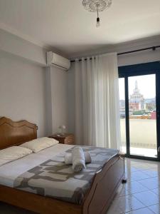 a bedroom with a large bed and a large window at Klara's Apartment in Fier