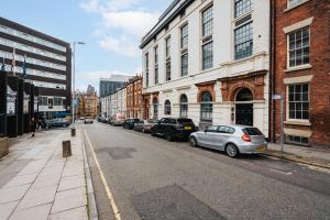 a city street with parked cars and buildings at Liverpool Warehouse Flat - Sleeps 5, WiFi, Free On-Site Parking in Liverpool