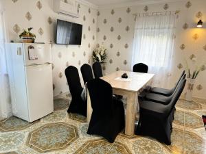 a dining room with a table and chairs and a refrigerator at Flamingó Apartman Kiskunmajsa in Kiskunmajsa