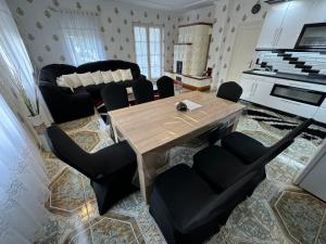 a living room with a wooden table and black chairs at Flamingó Apartman Kiskunmajsa in Kiskunmajsa