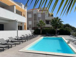 a swimming pool with lounge chairs next to a building at Villa Aquamarine Apartments in Novalja