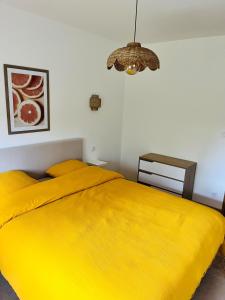 a bedroom with a large yellow bed with a chandelier at Gîte du dousset in Esclottes