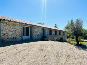 a stone house with a gravel driveway in front of it at Gîte du dousset in Esclottes