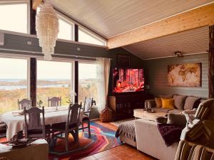 a living room with a table and a couch and a television at Atlantis cabin with sauna and great views in Vevang
