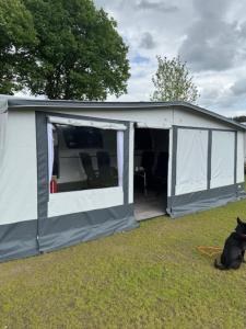 un gatto nero seduto davanti a una tenda di Premium Wohnwagen Nr 12 im Heide Resort Brüggen a Brüggen Altre 5 foto