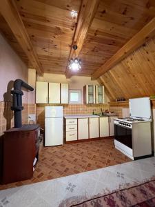a large kitchen with white appliances and wooden ceilings at Guest house Crvenkapa in Gusinje