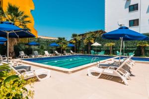 ein Swimmingpool mit Liegestühlen und Sonnenschirmen in der Unterkunft KURTI Hotel in Golem