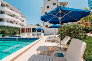 ein Pool mit Liegestühlen und Sonnenschirmen neben einem Hotel in der Unterkunft KURTI Hotel in Golem