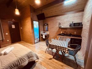 a room with a bed and a table and a kitchen at Chalés Canto da Serra in São Bento do Sapucaí
