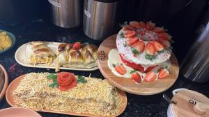 Ein Tisch mit Tellern voller Speisen, darunter Kuchen und Erdbeeren in der Unterkunft Otto Hotel in Governador Valadares