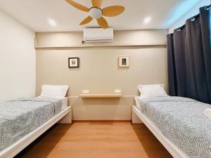 two beds in a room with a ceiling fan at WhiteZen Family Homestay 9Room for 20pax Central Penang in Jelutong