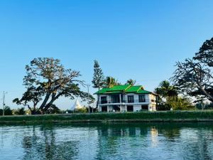 a house with a green roof next to a body of water at Tissa Yala Lake View Hotel in Tissamaharama