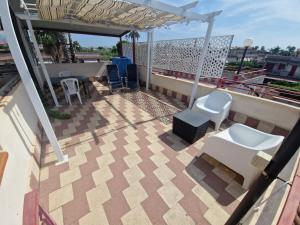 a balcony with two white chairs and a table at Stone beach holiday home in Mascali