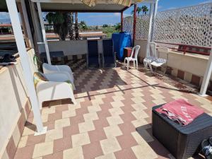 a patio with chairs and a table on a balcony at Stone beach holiday home in Mascali