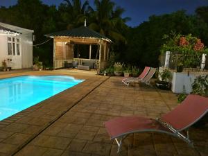 a swimming pool with two chairs and a gazebo at Lazy Tilapia in Baie du Tombeau