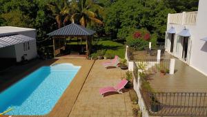 a swimming pool with chairs next to a house at Lazy Tilapia in Baie du Tombeau