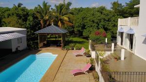 a backyard with a swimming pool and chairs next to a house at Lazy Tilapia in Baie du Tombeau