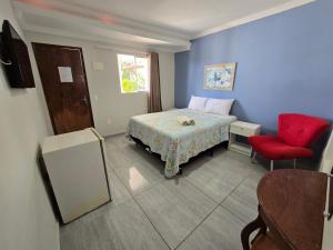 a bedroom with a bed and a red chair at Porto De Galinhas Pousada Raízes Do Porto in Porto De Galinhas