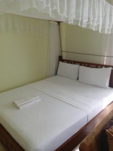 a bed with white sheets and pillows in a room at JOLANDA STUDIO APARTMENTs in Mtwapa +3 photos