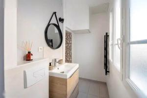 une salle de bain blanche avec un lavabo et un miroir dans l'établissement Logement St Malo Centre - Emplacement idéal 20 min à pied Intra-Muros & grande plage du Sillon, à Saint-Malo