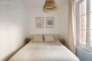 un lit blanc dans une chambre avec une fenêtre dans l'établissement Logement St Malo Centre - Emplacement idéal 20 min à pied Intra-Muros & grande plage du Sillon, à Saint-Malo