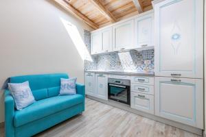 a blue couch in a kitchen with white cabinets at Su Chélu in Villasimius