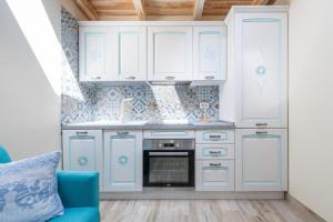 a kitchen with white cabinets and a blue chair at Su Chélu in Villasimius