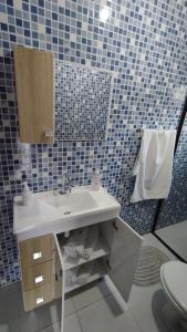 a bathroom with a sink and a blue tiled wall at Casa inteira I - 2 quartos in Pomerode +11 photos