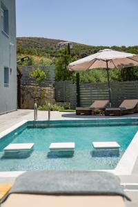 a swimming pool with an umbrella and two loungers at Olive Scent in Gouves