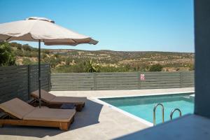 a swimming pool with an umbrella and a chair at Olive Scent in Gouves