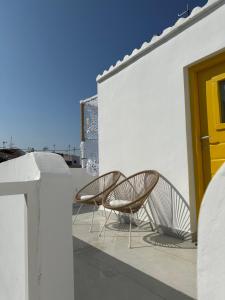 twee stoelen op een balkon met een gele deur bij Marias Home in Kithnos