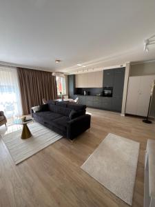 a living room with a black couch and a kitchen at Apartament Symsar in Lidzbark Warmiński