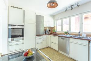 a kitchen with white cabinets and a bowl of fruit on a table at Haus am Rebberg in Öhningen +6 photos
